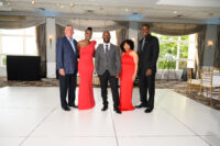 Five nicely dressed people in a ballroom